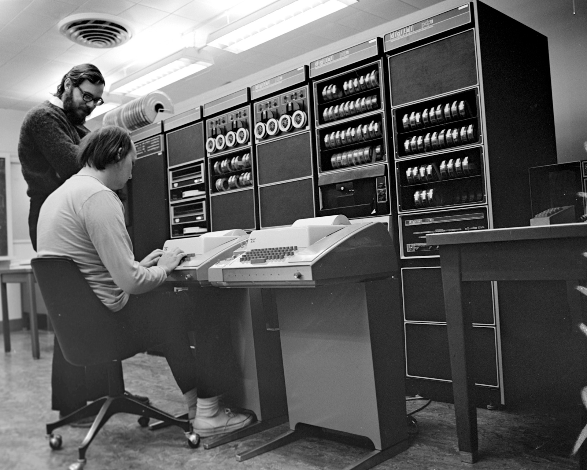 Ken Thompson (assis devant un téléscripteur) et Dennis Ritchie travaillant sur le PDP-11